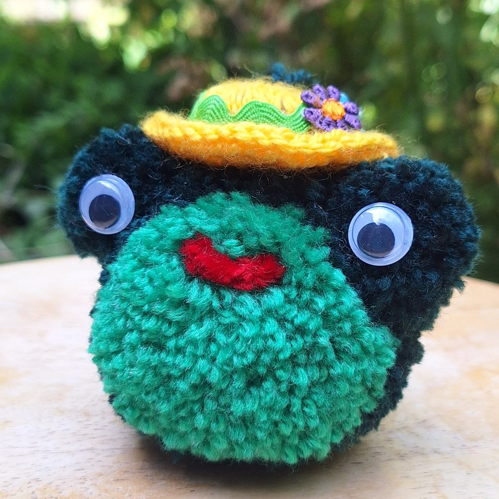 Pom pom yarn frog with crochet plastic bottle cap hat