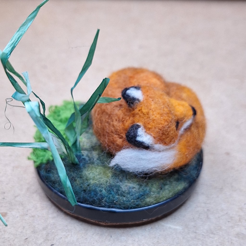 Needle-felted sleeping fox on woolly grass jar lid